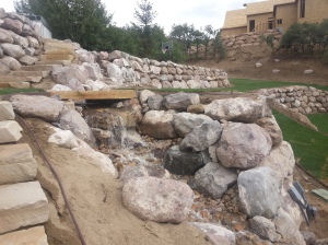 Landscaping in Bountiful Utah, landscaper installing, Huge rock boulder retaining walls, rock walls, Retaining, double pump energy efficient water features, walls, landscaping, Belgard natural gas fire pit, Belgard Mega Laffit Paver patio around the pool, Belgard Paver walls in Belair with belair caps, Paver fire pits, trees, topsoil, sod from bio grass sod farms, Landscape construction, landscaping in Bountiful, Utah